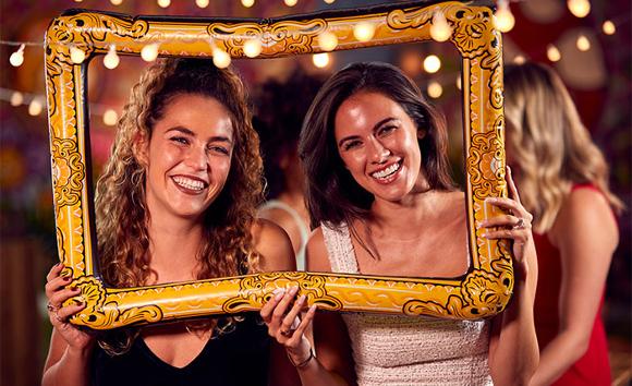 Two happy women posing inside a picture frame